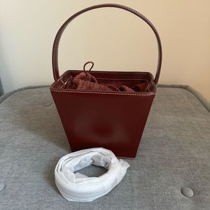 STAUD Rigid bucket bag in wine-colored box New